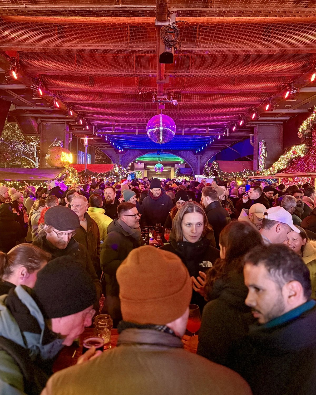 Gäste unter der beleuchteten Hochbahn am Nollendorfplatz mit Discokugel – Christmas Avenue Berlin