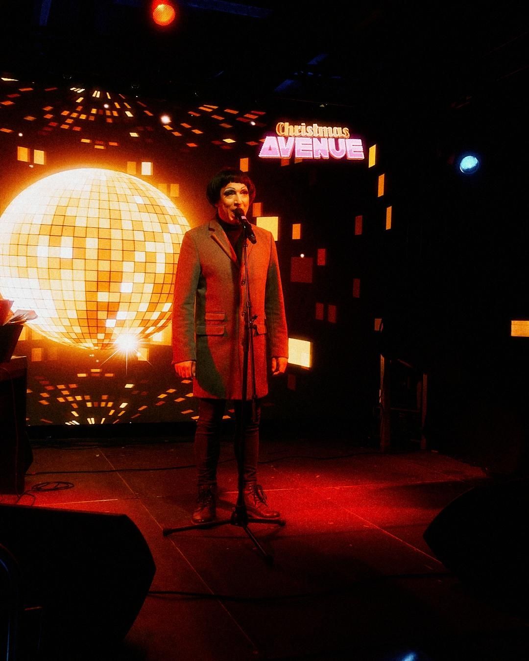 Eine Drag-Künstlerin steht im Scheinwerferlicht auf der Bühne der Christmas Avenue.