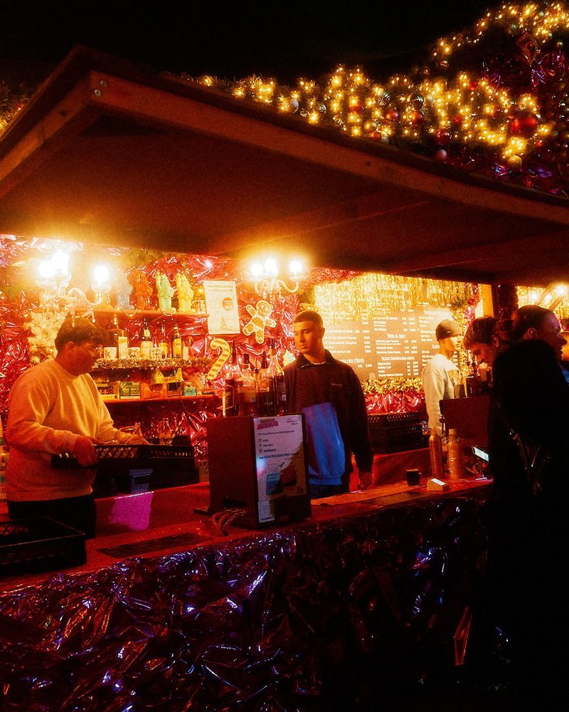Auf der Christmas Avenue schenken Verkäufer an einem dekorierten Stand Getränke an Besucher aus.